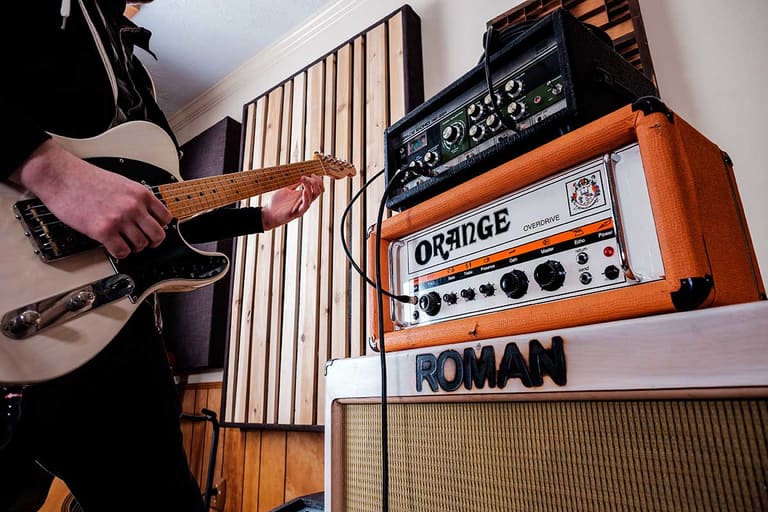 A guitarist playing beside stacked vintage amplifiers and a Roland Space Echo at Aria Recording Studio